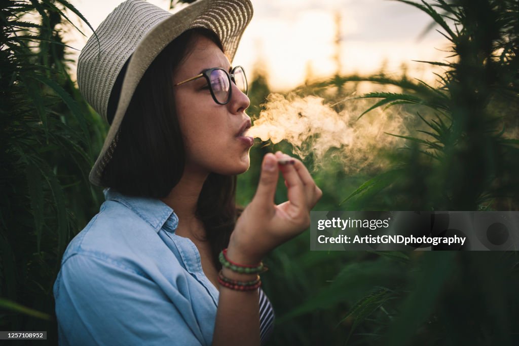 Belle femme fumant la marijuana dans la plantation.