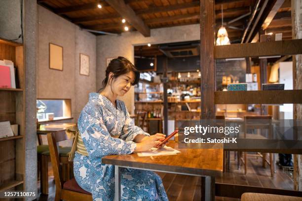 japanse vrouw in yukata die slimme telefoon in traditioneel stijl japans café gebruikt - shitamachi stockfoto's en -beelden