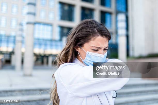 young female healthcare worker sneezing. - respiratory disease stock pictures, royalty-free photos & images