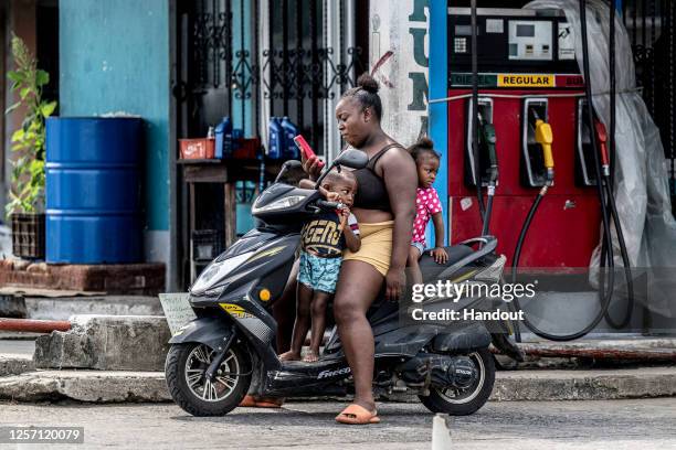 In this handout image provided by Red Bull, Locals wait by a petrol pump during the Red Bull Cliff Diving World Series "Dive into Guatemala" on April...