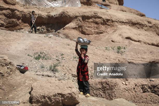 An Afghan child carries bucket on his head near the caves, while many people struggle with drought, hunger, disease and malnutrition in Bamyan...