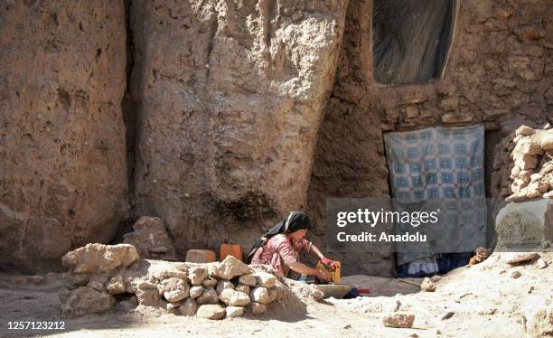 An Afghan woman cooks on fire in front of a cave, while many people struggle with drought, hunger, disease and malnutrition in Bamyan Province,...