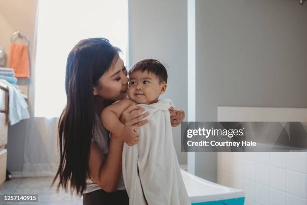 mother snuggles toddler little boy while wrapping him in towel after his bubble bath - mother and baby taking a bath stock pictures, royalty-free photos & images