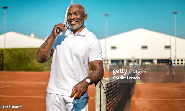 a handsome black middle aged male tennis player on the court - amateur tennis man stock pictures, royalty-free photos & images