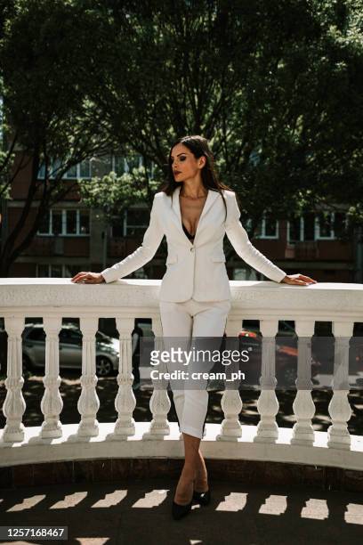 smiling woman wearing white suit outdoors - white suit stock pictures, royalty-free photos & images