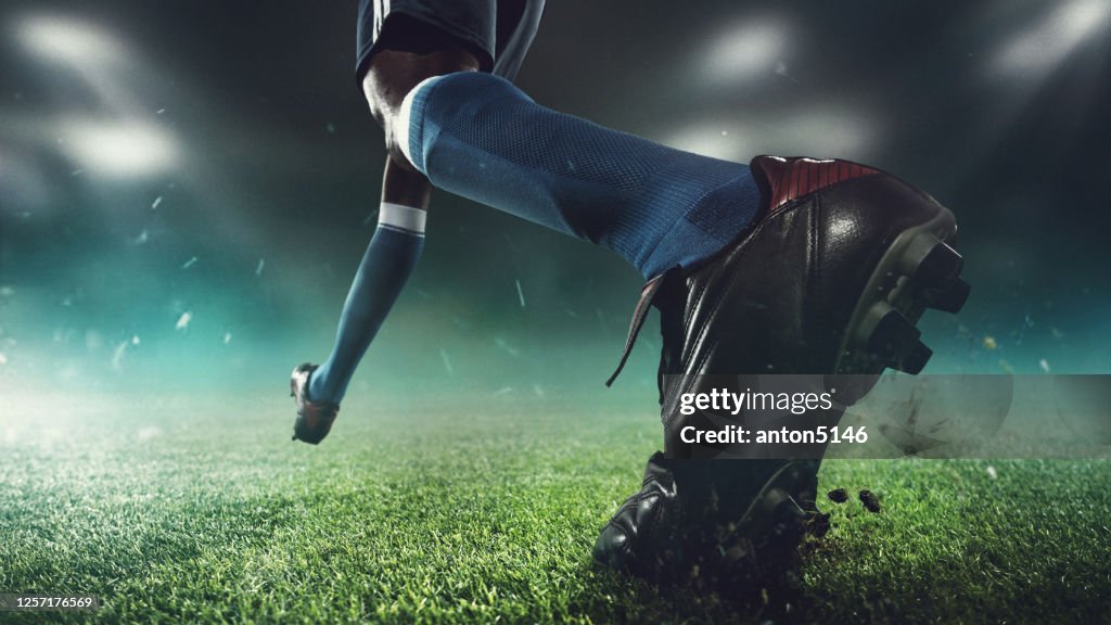 Close up football or soccer player at stadium in flashlights - motion, action, activity concept