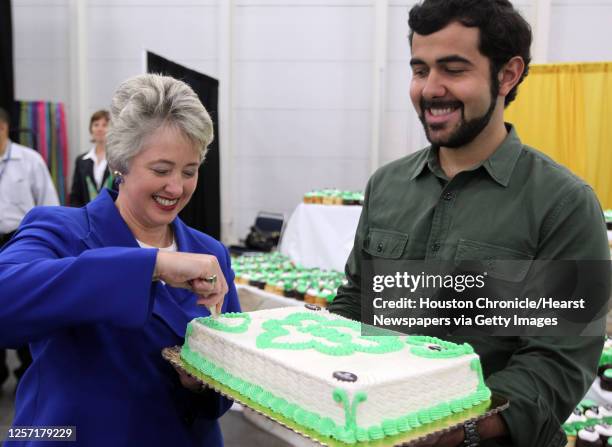 Houston Mayor Annise Parker left, cuts the Girls Scouts 100th Anniversary cake while Phoenicia Foods Haig Tcholakian right holds the cake during the...