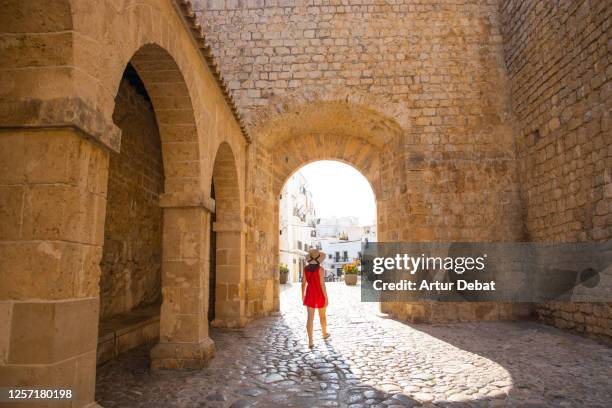 woman in red dress walking in the old city of the ibiza town with summer style. mujer con vestido rojo en la parte antigua del pueblo de ibiza. - summer spain stock-fotos und bilder