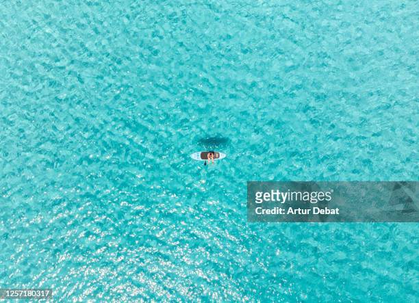 drone view of guy doing paddle surf in the crystal water of the formentera island in the mediterranean sea. - ibiza island stock-fotos und bilder