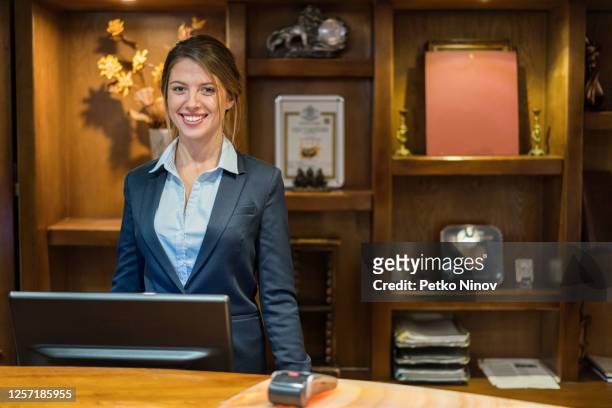 hotelrezeptionist lächelnd in die kamera - hotel stock-fotos und bilder