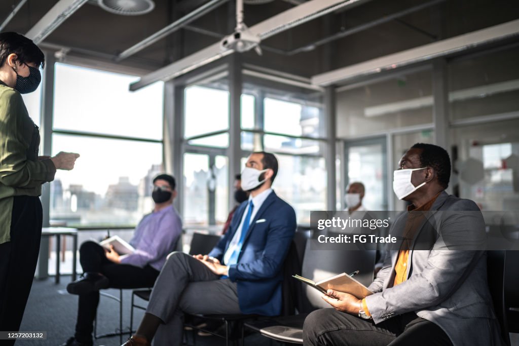 Business people attending a seminar with social distancing and face mask