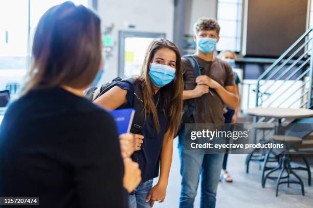 high school teacher greeting students and all wearing face masks - secondary school covid stock pictures, royalty-free photos & images