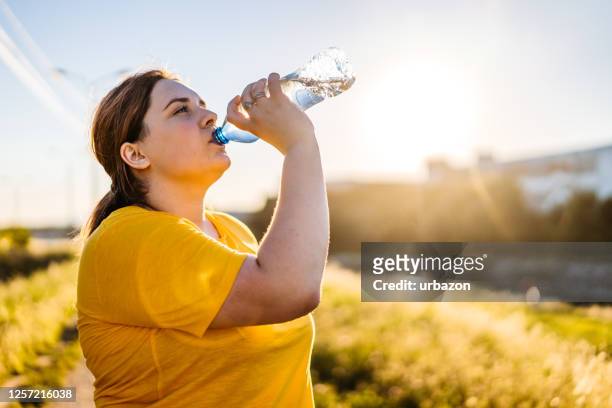 oversized woman drinking water after running - drinking water stock pictures, royalty-free photos & images