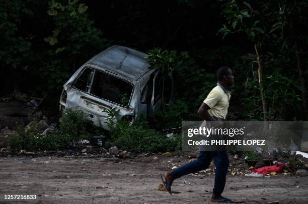 Pedestrian walks past an abandonned car wreck before the dismantlement operation of the shantytown of "Talus 2" district in Koungou, before its...