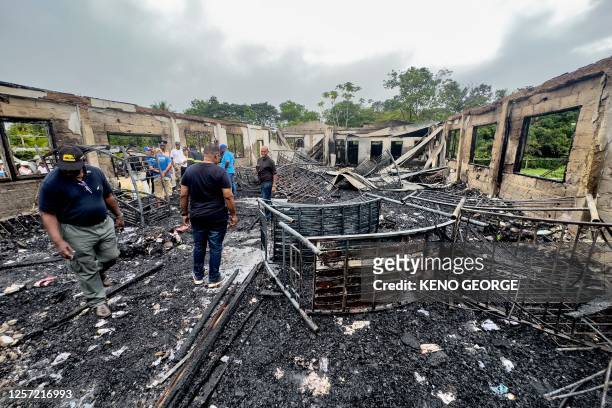 Investigators and government employees inspect the school dormitory where a fire killed at least 19 people in Mahdia, Guyana on May 22, 2023. At...