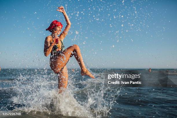 glückliche junge frau mit gefärbten roten haaren im urlaub - wasser treten stock-fotos und bilder