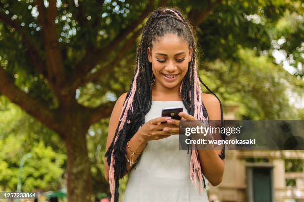 portret van jonge afrovrouw die smartphone in een openbaar park gebruikt - belém brazilië stockfoto's en -beelden