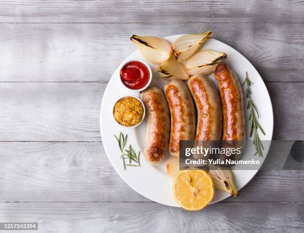 spicy homemade baked sausages with baked vegetables and spices on a light wooden background. close-up, copy space. - insaccato foto e immagini stock