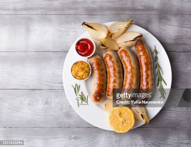 spicy homemade baked sausages with baked vegetables and spices on a light wooden background. close-up, copy space. - sausage stock pictures, royalty-free photos & images