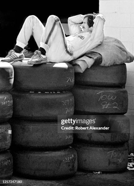 Driver Dale Earnhardt Sr. Relaxes on stacks of racing tires in the speedway garage area prior to the start of the 1982 Daytona 500 stock car race at...