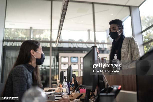 businesswoman talking to receptionist on entrance of office's lobby - with face mask - hospital reception stock pictures, royalty-free photos & images