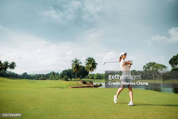 asian chinese young female golfer with sunglasses playing golf on the golf course - golf driver stock pictures, royalty-free photos & images