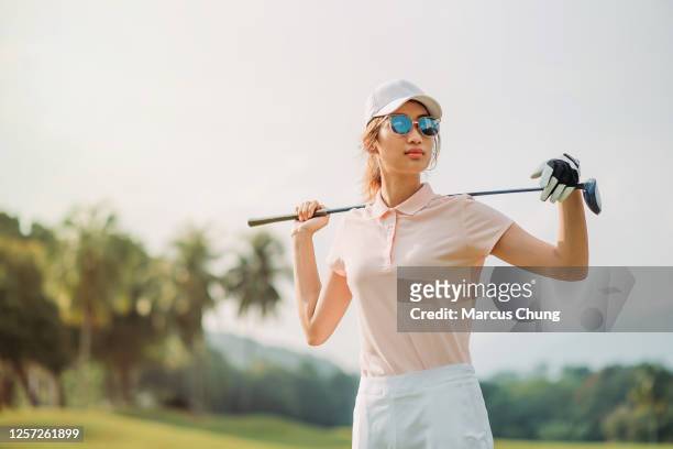 portrait of a asian chinese female golfer holding the golf club at the course - polo shirt imagens e fotografias de stock