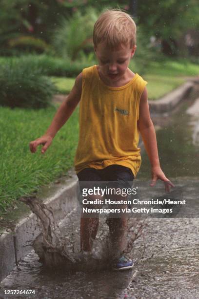 Jake Mardon splashes in a mud puddle near his home in the Heights, Tuesday afternoon with his brother, Sam , after a brief rainstorm in the area.
