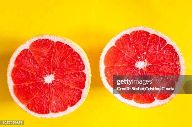 red grapefruit slices on a yellow background - pink grapefruit stock pictures, royalty-free photos & images