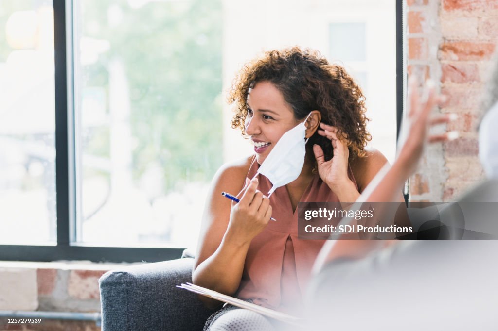 De therapeut zet beschermend gezichtsmasker vóór therapiezitting op