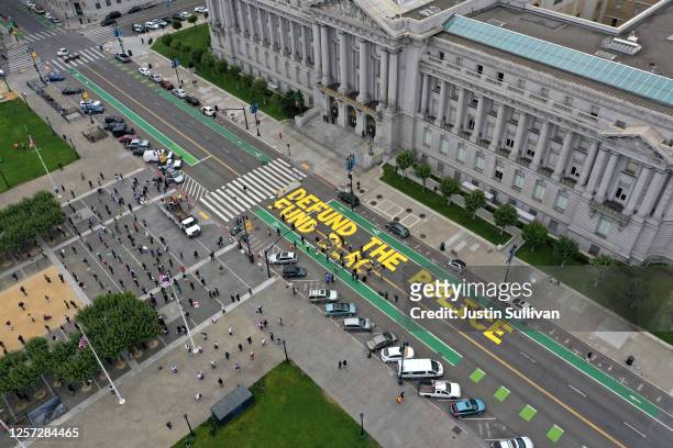 Protesters paint a mural that says 'defund the police' during a Strike For Black Lives demonstration outside of San Francisco City Hall on July 20,...