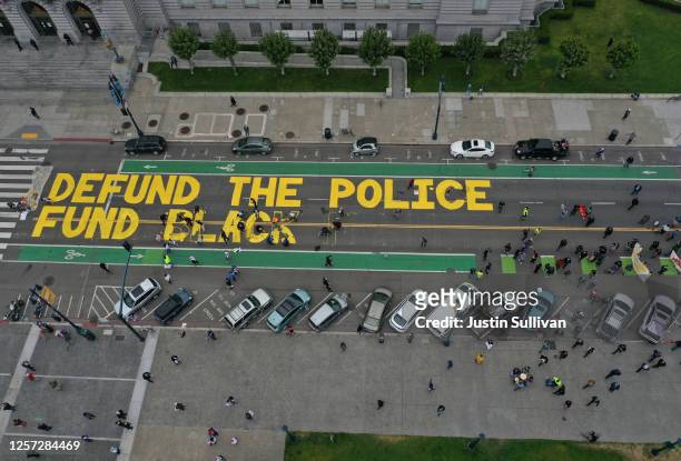 Protesters paint a mural that says 'defund the police' during a Strike For Black Lives demonstration outside of San Francisco City Hall on July 20,...