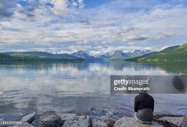 woman looking at the beautiful natural scenery of glacier national park's lake mcdonald area during the summer in montana, usa. - montana moody sky stock pictures, royalty-free photos & images