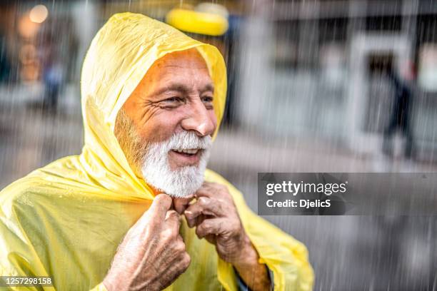 senior man in raincoat walking in rain. - drenched stock pictures, royalty-free photos & images