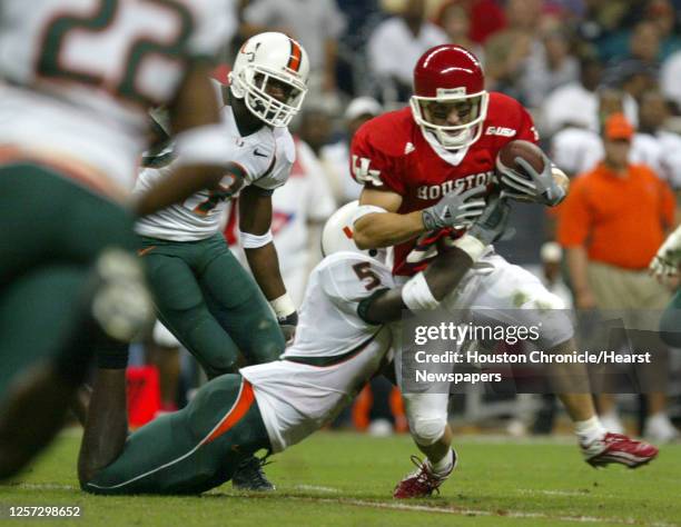 Houston's, Perry McDaniel tries to shake the tackle of Miami's, Greg Threat during the first half of the University of Houston-Miami football game at...