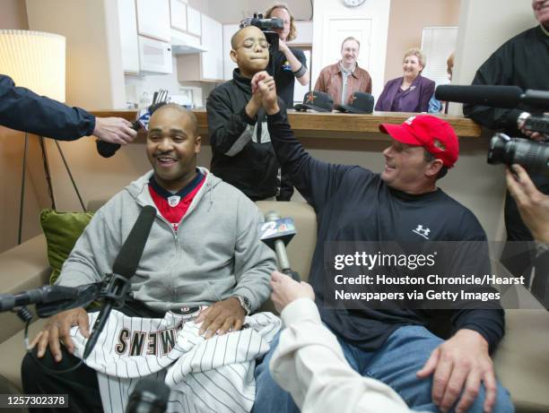 Roger Clemens high-fives Chad Comer as Chris Comer, left, finish a press conference in the living room after the crew of TLC's While You Were Out...