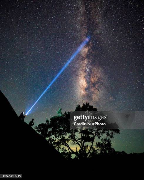 Milky way is shining over the makeshift huts erected in trees in Galgamuwa, Sri Lanka, on May 22, 2023. Farmers are spending the night in these...