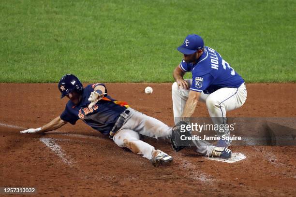 Myles Straw of the Houston Astros slides into home plate to score on a wild pitch as pitcher Greg Holland of the Kansas City Royals covers during the...