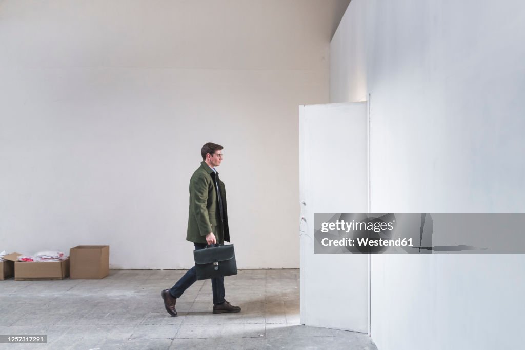 Businessman with briefcase leaving sparse room