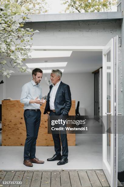 two businessmaen standing in open office door, talking - open day 2 stock-fotos und bilder
