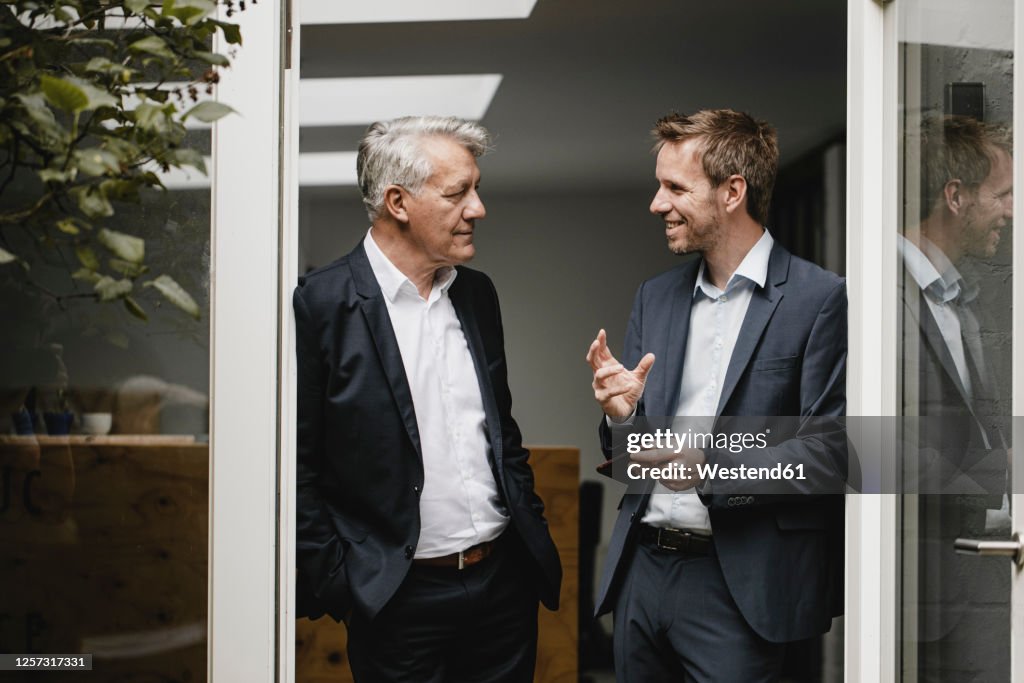 Two businessmen standing in office door, talking