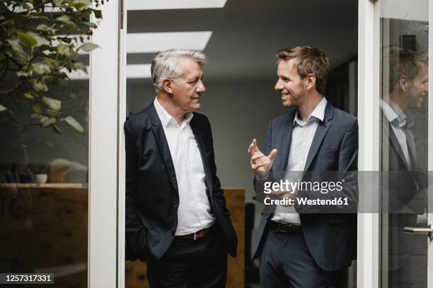 two businessmen standing in office door, talking - gespräch stock-fotos und bilder