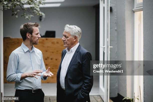 two businessmaen standing in open office door, talking - branch office stock pictures, royalty-free photos & images