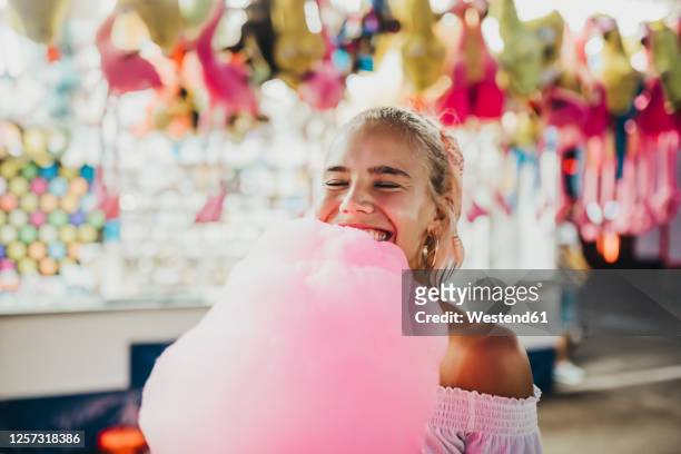 close-up of smiling young woman with eyes closed holding cotton candy at amusement park - cotton candy stock pictures, royalty-free photos & images