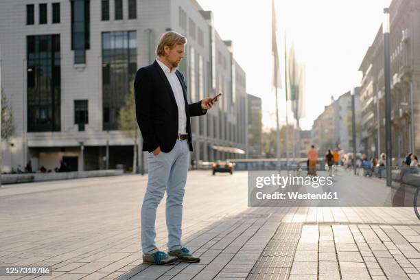 businessman using smartphone in the city - man side standing stock-fotos und bilder