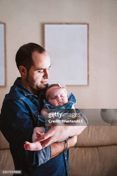 father carrying sleeping baby girl in living room at home - babyhood photos et images de collection
