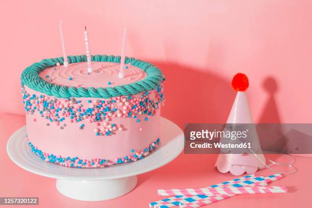 cake stand with strawberry birthday cake, drinking straws and party hats - birthday cake stock pictures, royalty-free photos & images