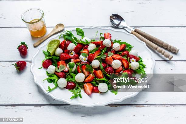 plate of vegetarian summer salad with lime, arugula, strawberries, mozzarella, mint and daisies - mozzarella stock pictures, royalty-free photos & images