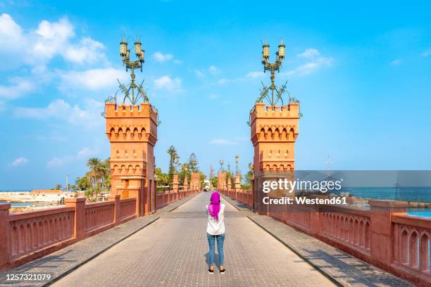 egypt, alexandria, rear view of woman standing on montaza bridge - alexandria egypt stock-fotos und bilder