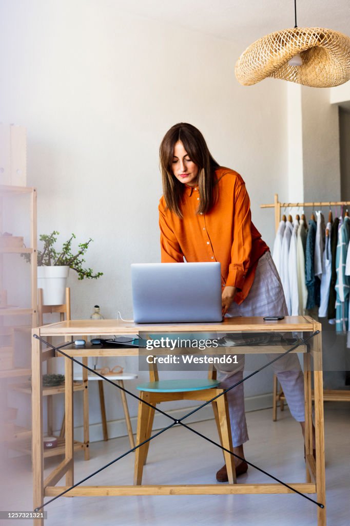 Female fashion designer working at home at desk with laptop